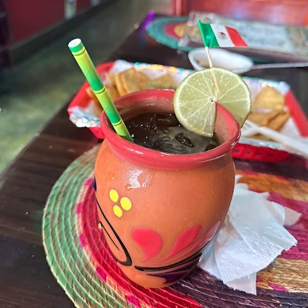 Mexican drink in a clay jar with a lime slice and a small Mexican flag.